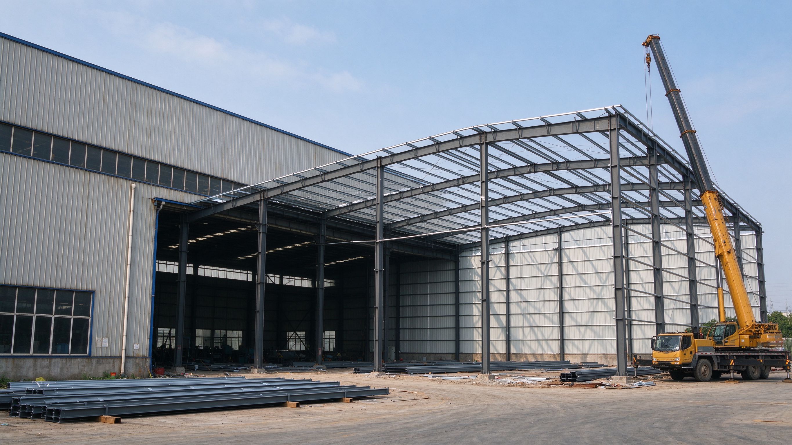 New steel bay added next to an existing steel building (illustrative concept image)
