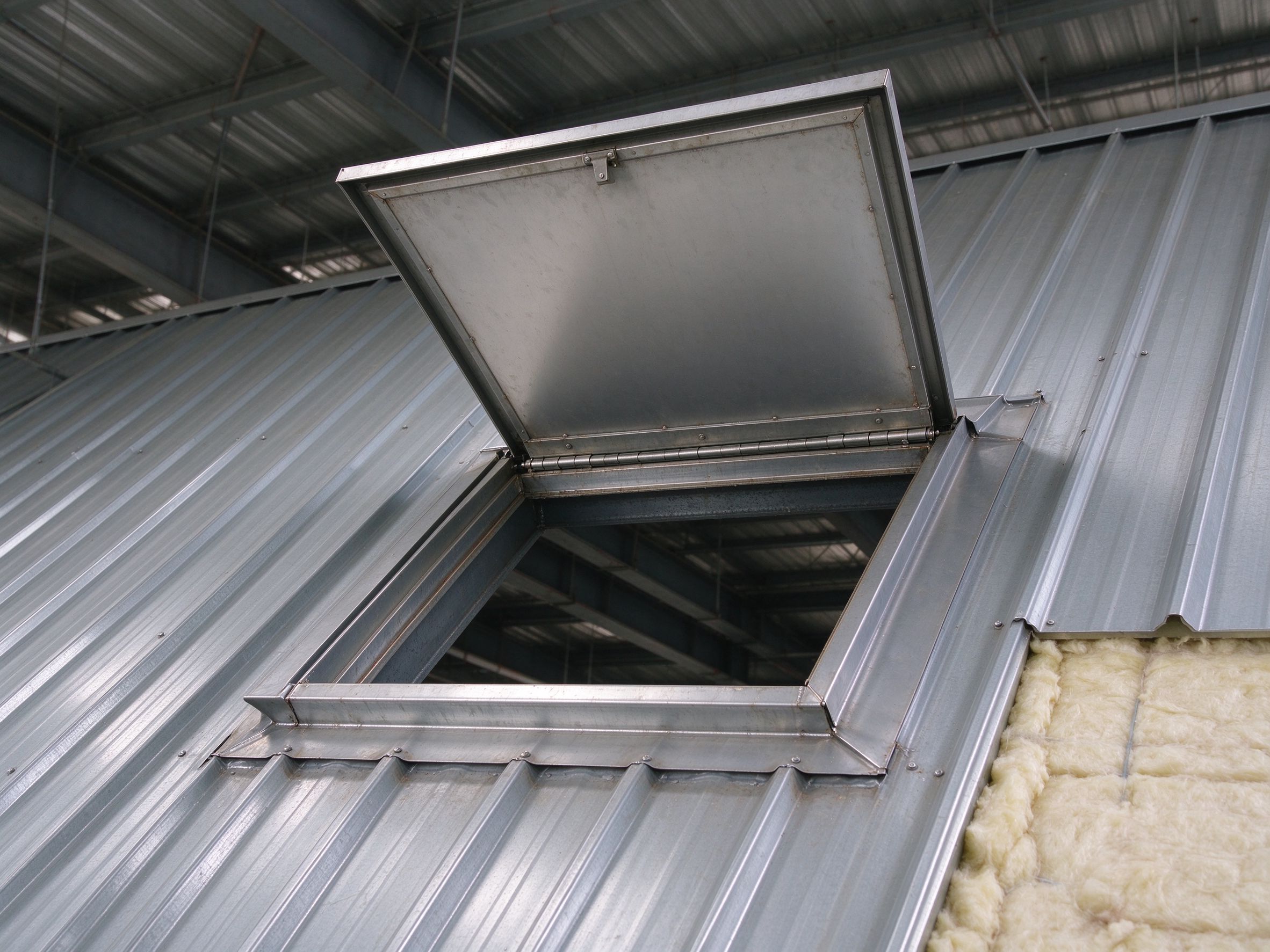 Open roof hatch with flashing curb on a steel roof (illustrative concept image)